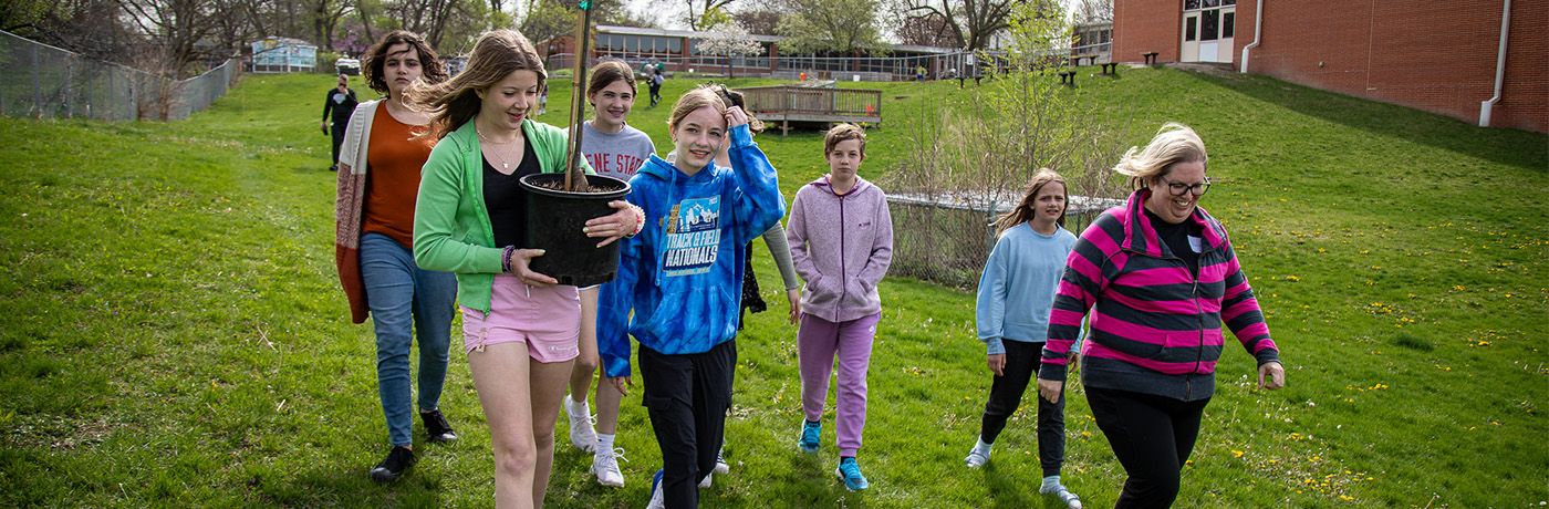 students planting a tree at cowles